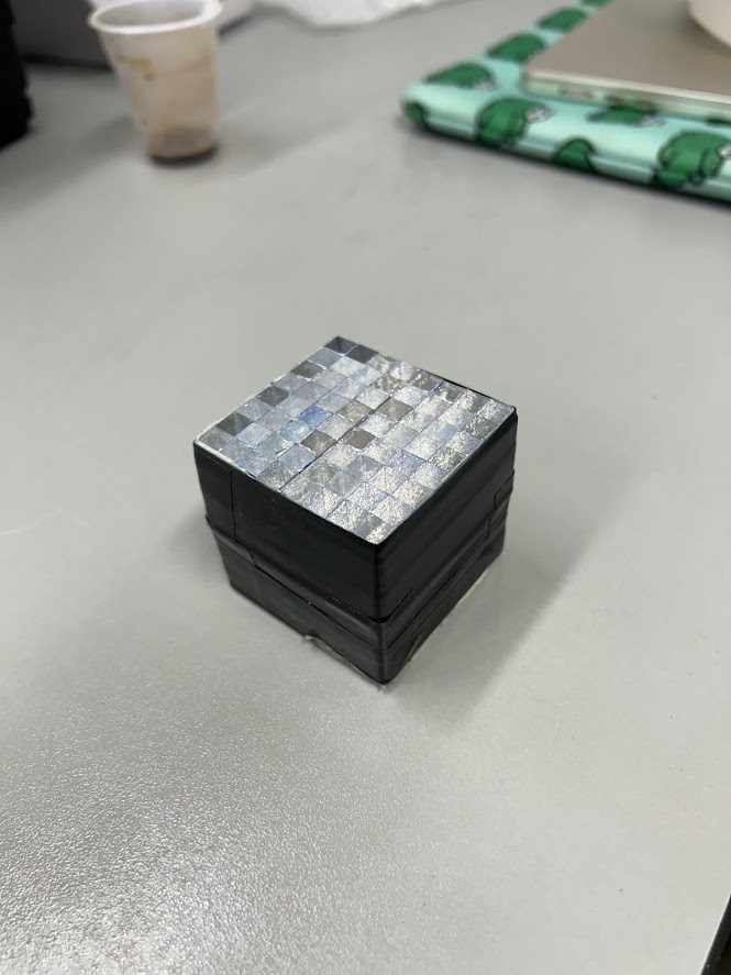 A small cube-shaped plastic scintillator block made from a 2D matrix of scintillating fibres, showing the cut cross-section
