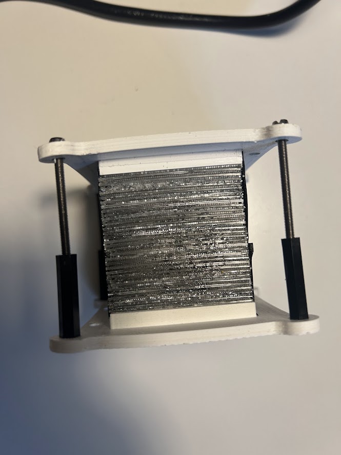 A jig holding a bundle of scintillating fibres wound flat before being set in optical cement