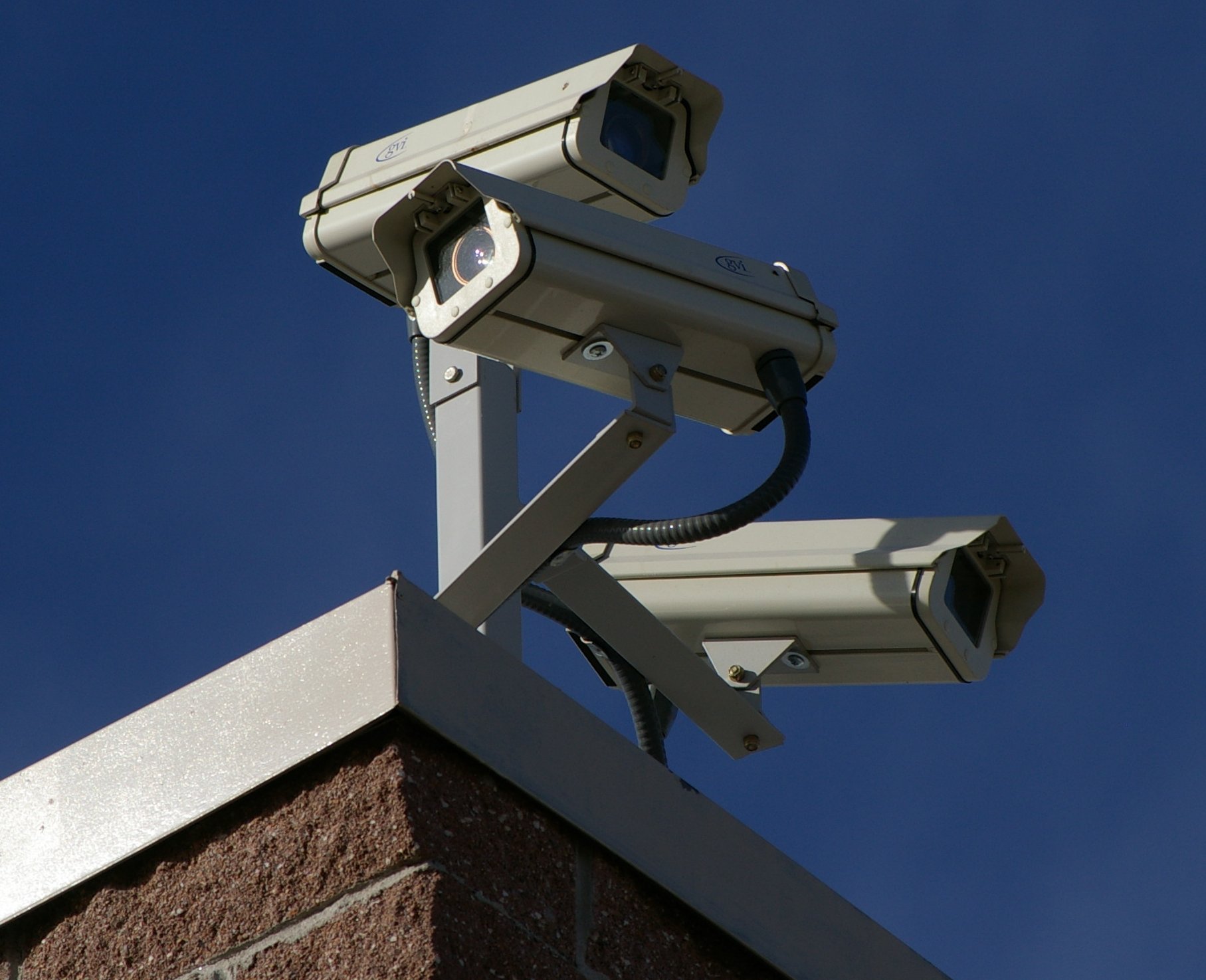 Three CCTV surveillance cameras mounted at different angles on the corner of a building